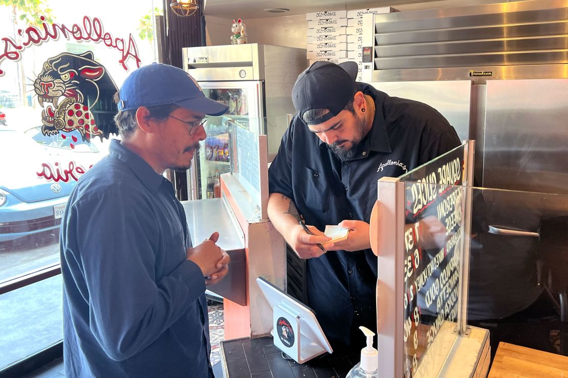 Justin De Leon, owner of Apollonia’s Pizzeria in Los Angeles, writes an order for a customer.