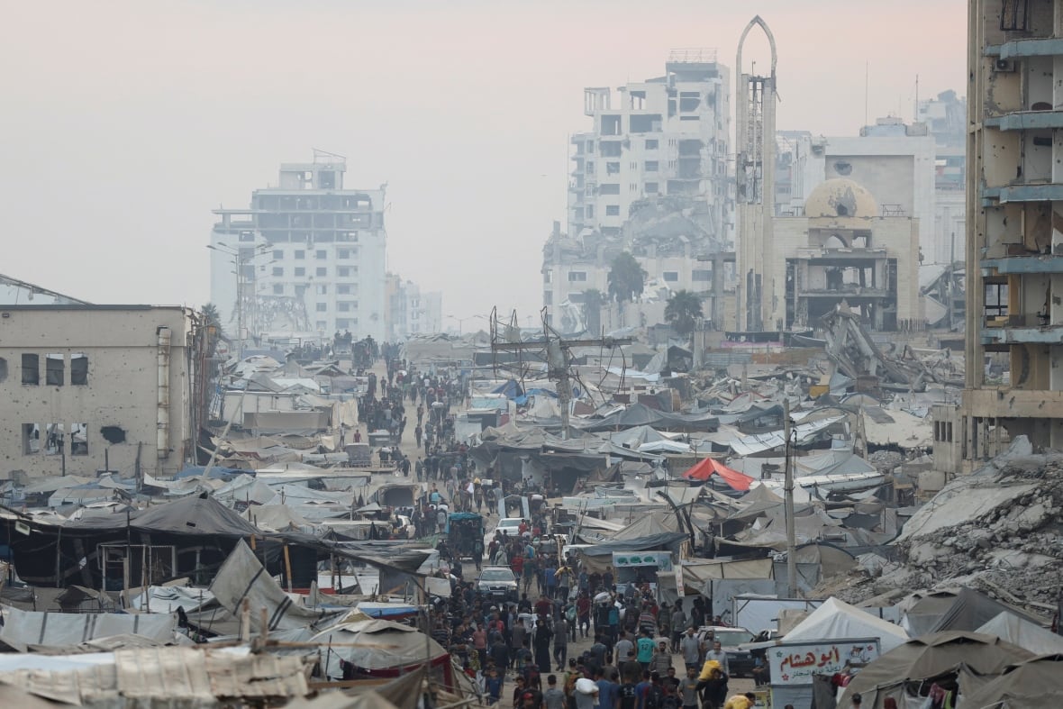 People walk through a destroyed city in Gaza.