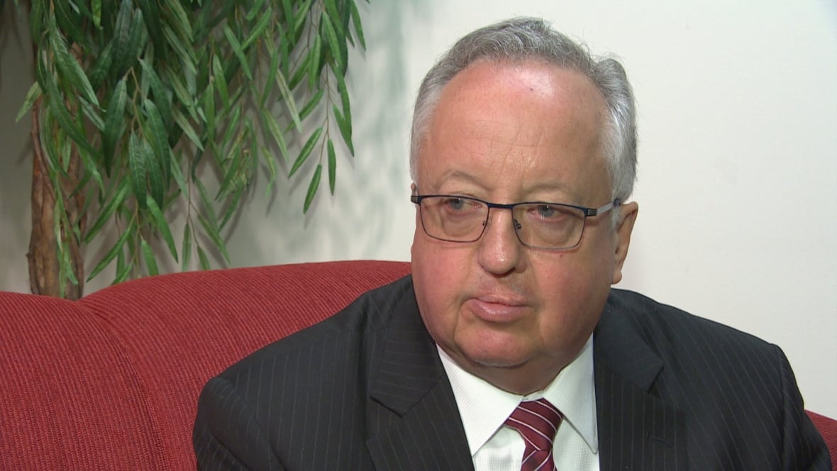 Man wearing glasses sitting on a couch.