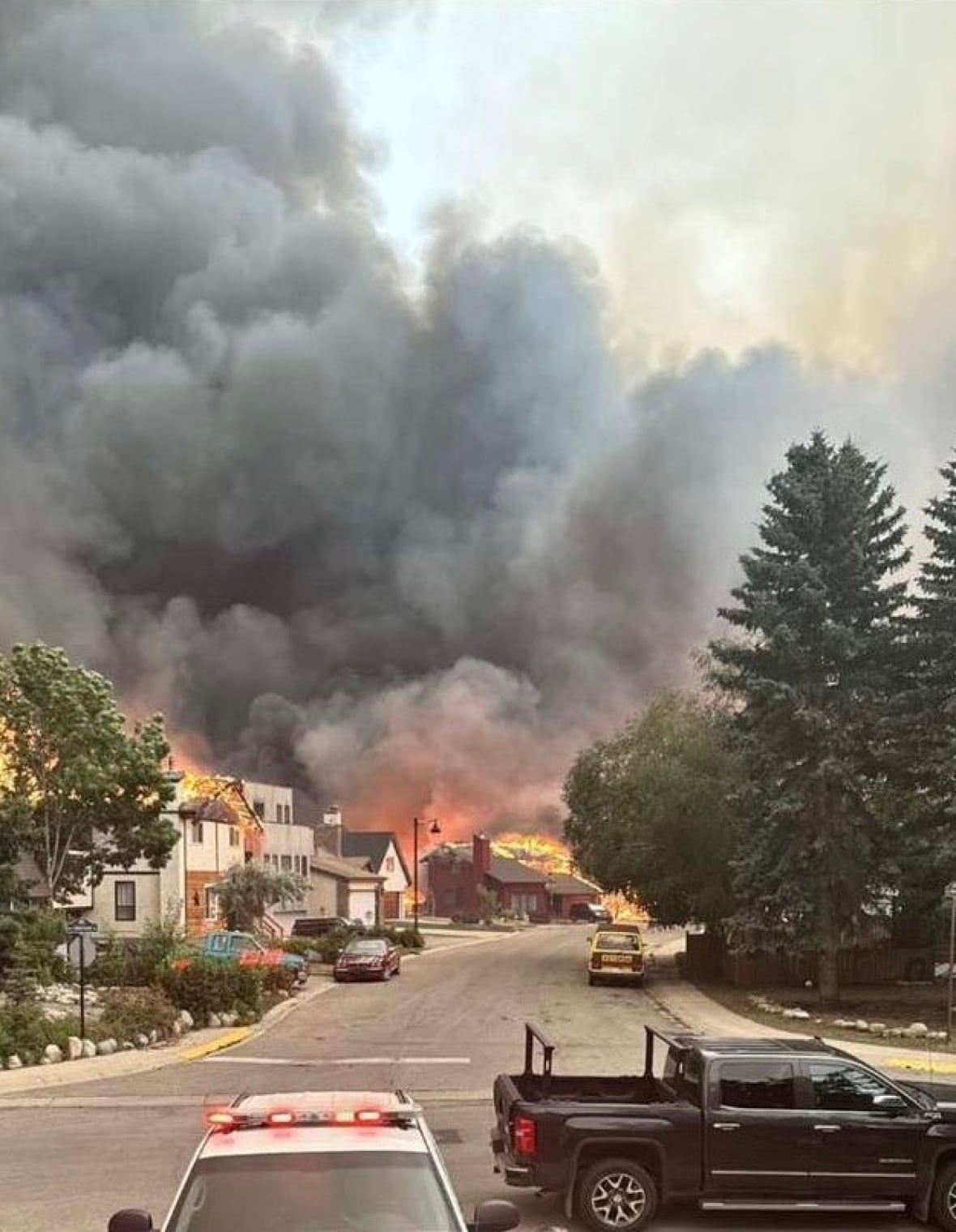 A large plume of smoke over trees.