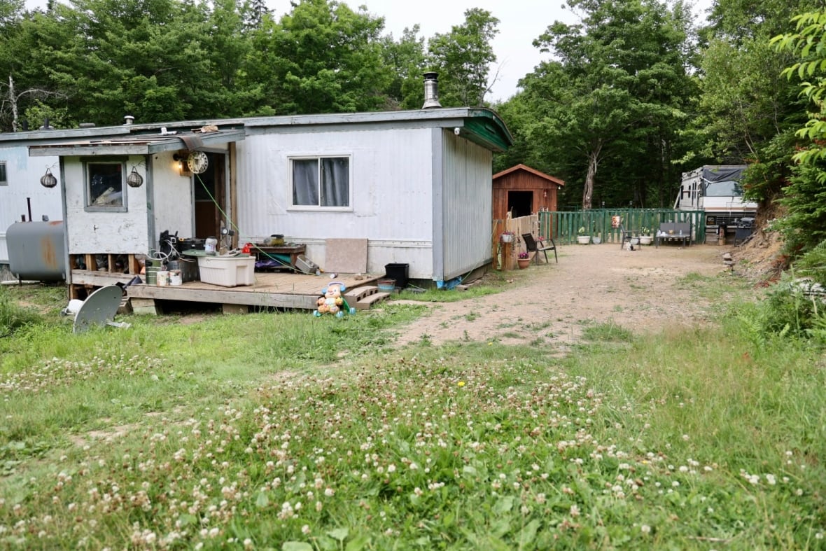 A mobile home is seen in foreground, and a travel trailer behind it. 