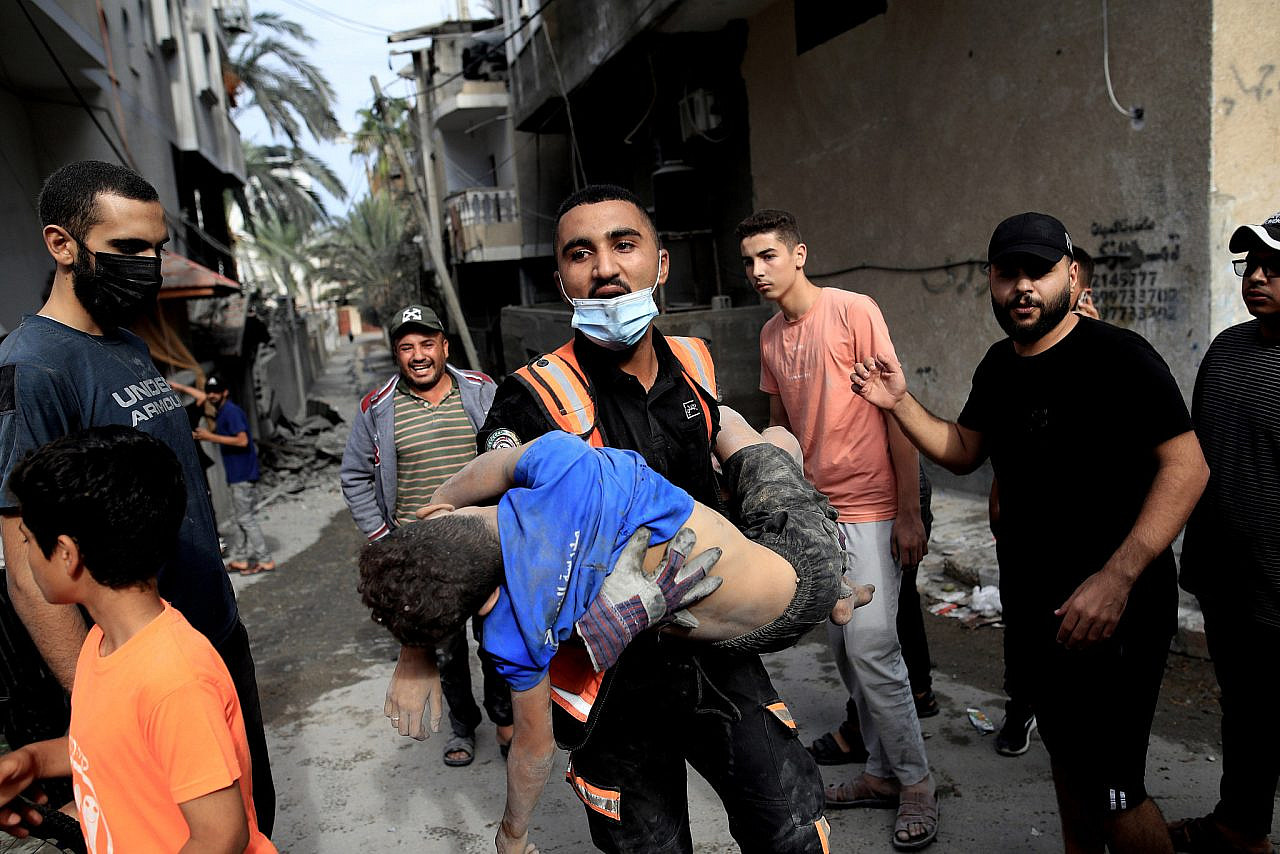 A member of the Palestinian Civil Defense carries a wounded child after Israeli airstrikes destroyed buildings in Rafah, southern Gaza Strip, October 17, 2023. (Mohammed Zaanoun/Activestills)