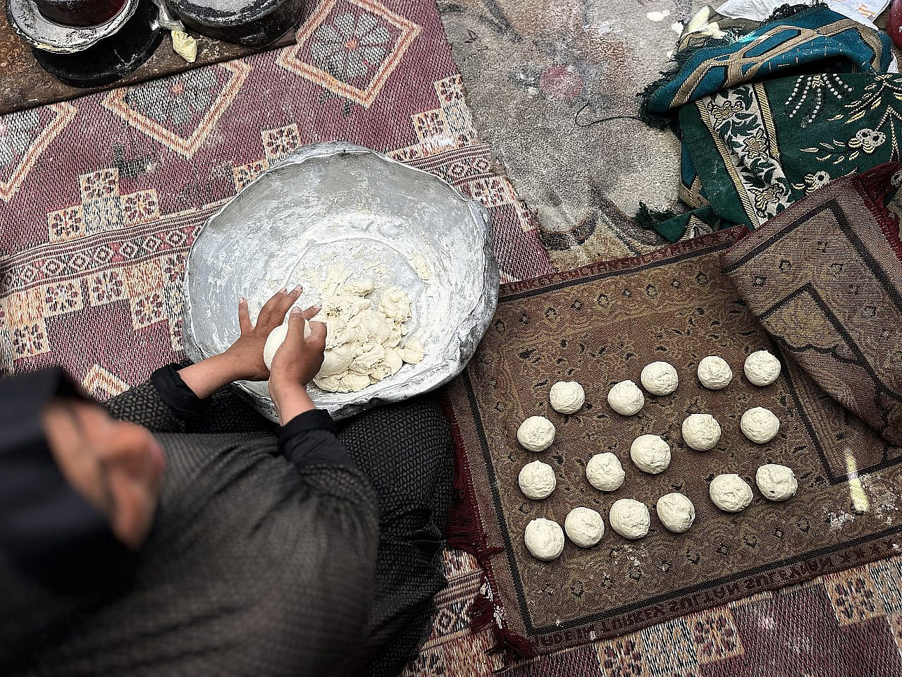 A displaced Palestinian woman makes bread in her tent, Al-Mawasi, southern Gaza Strip, July 13, 2025. (Doaa Albaz/Activestills)