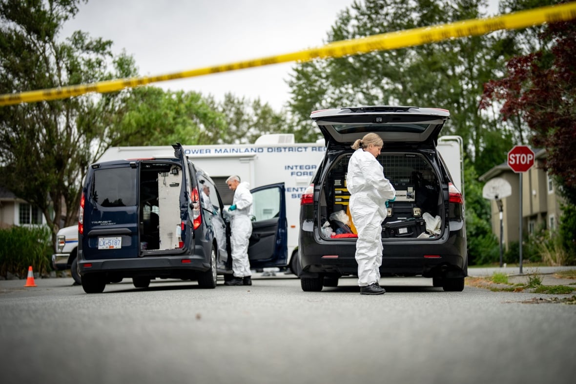 Two people dressed in white uniforms put on equipment in the middle of the street.