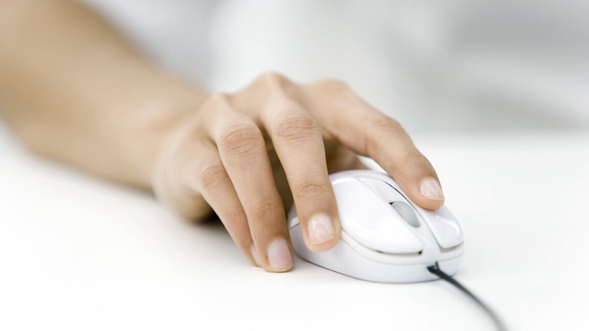 Close-up shot of a person's hand using a computer mouse