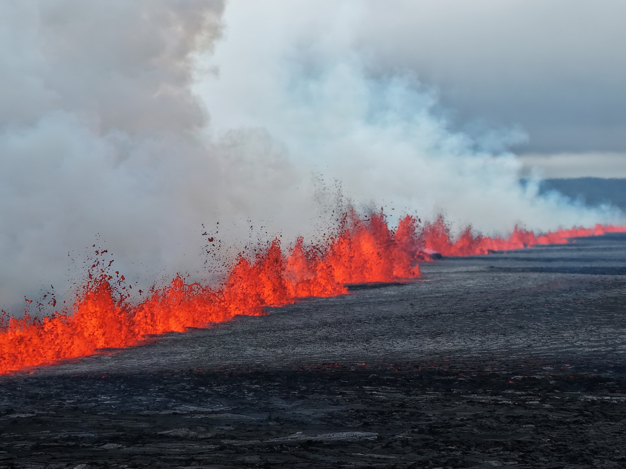 A photograph of lava erupting in a line out of the Sundhnúkur crater row fissure.