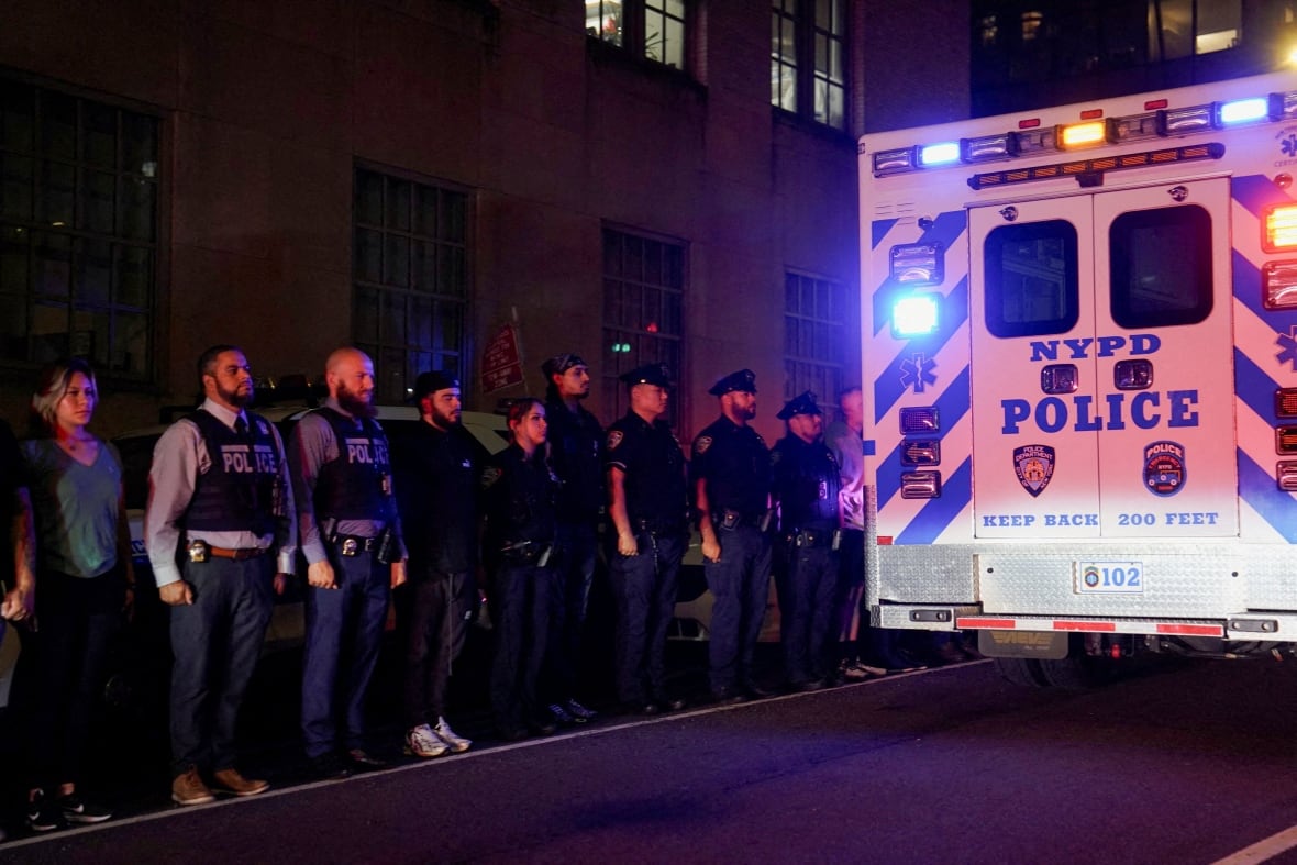 Police officers stand in a line for the ambulance transfer of a slain policeman.
