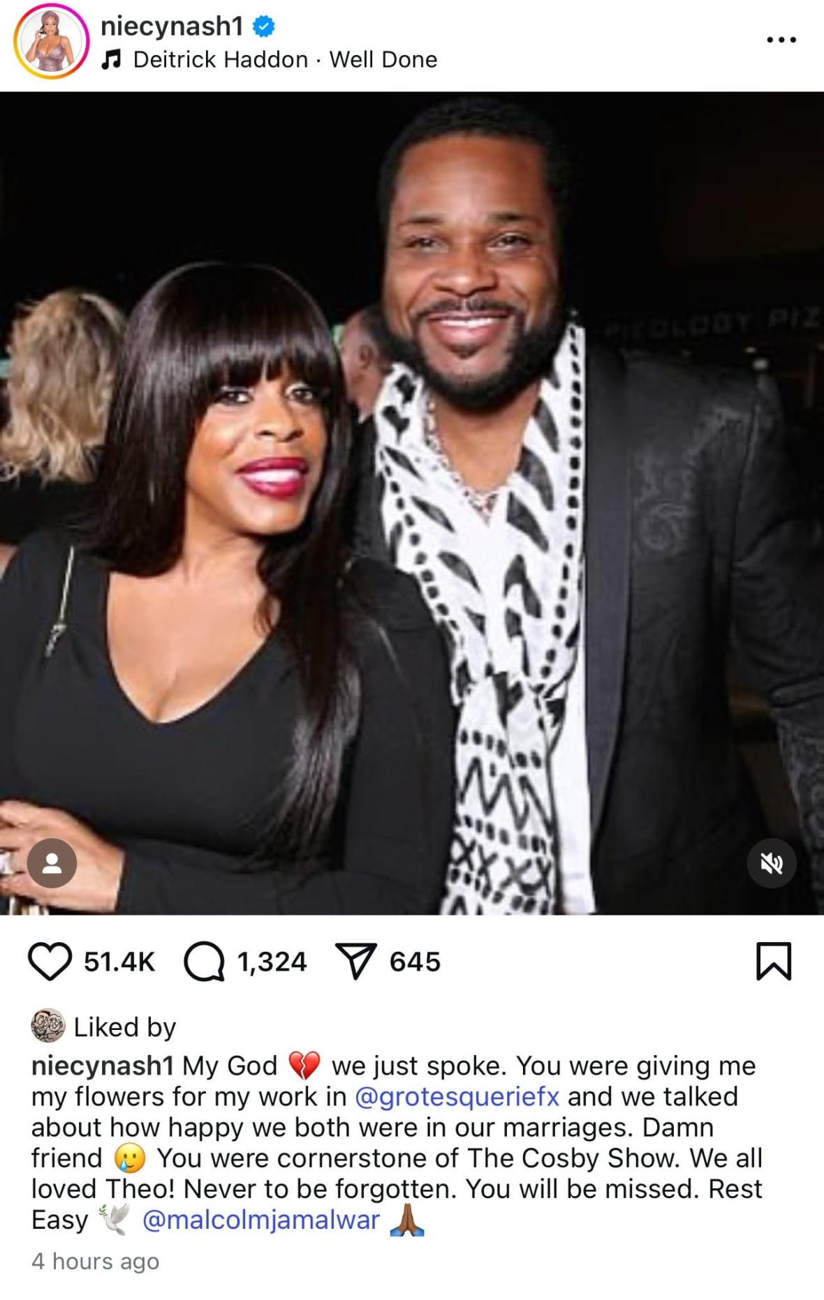 A woman with long black hair smiles as she stands next to a smiling man with short black hair and a black beard.