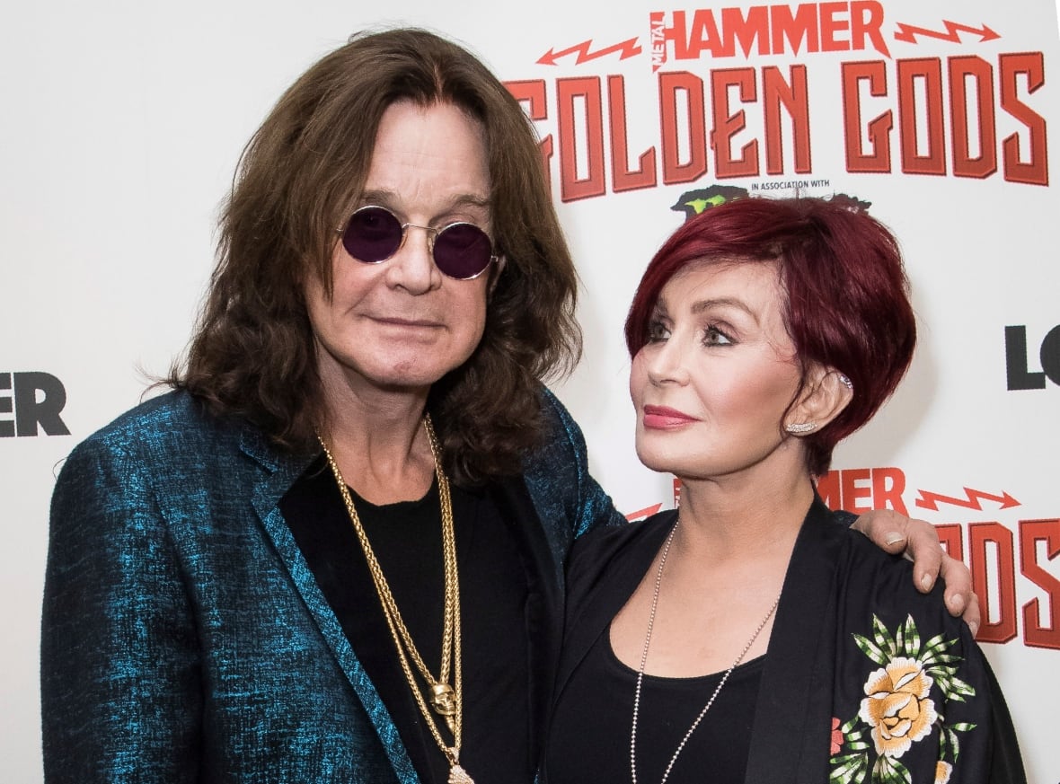 A man stands next to a woman while posing for a photo against a backdrop that reads "Metal Hammer Golden Gods."