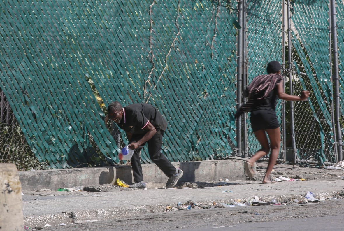 People seek cover amid gunfire between police and gangs in Port-au-Prince, Haiti.
