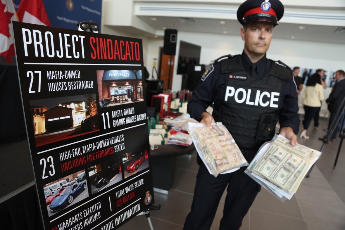 A police officer holds bags of money.