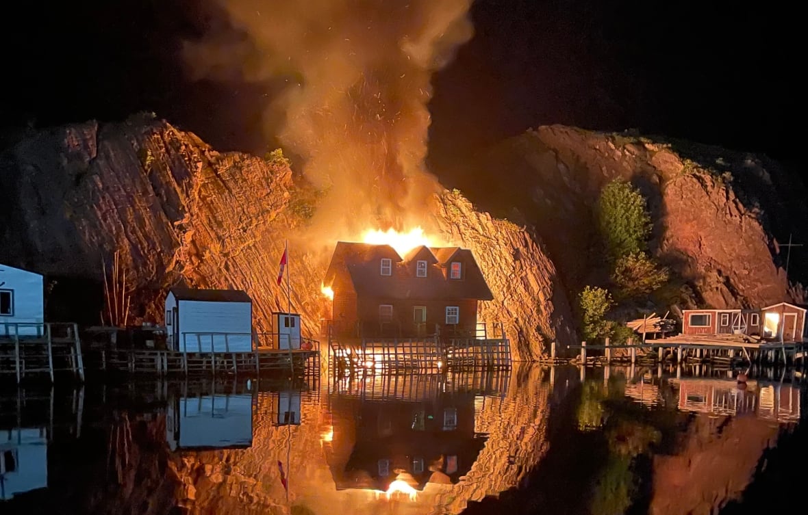 A fire burning a building, reflecting flames on water.