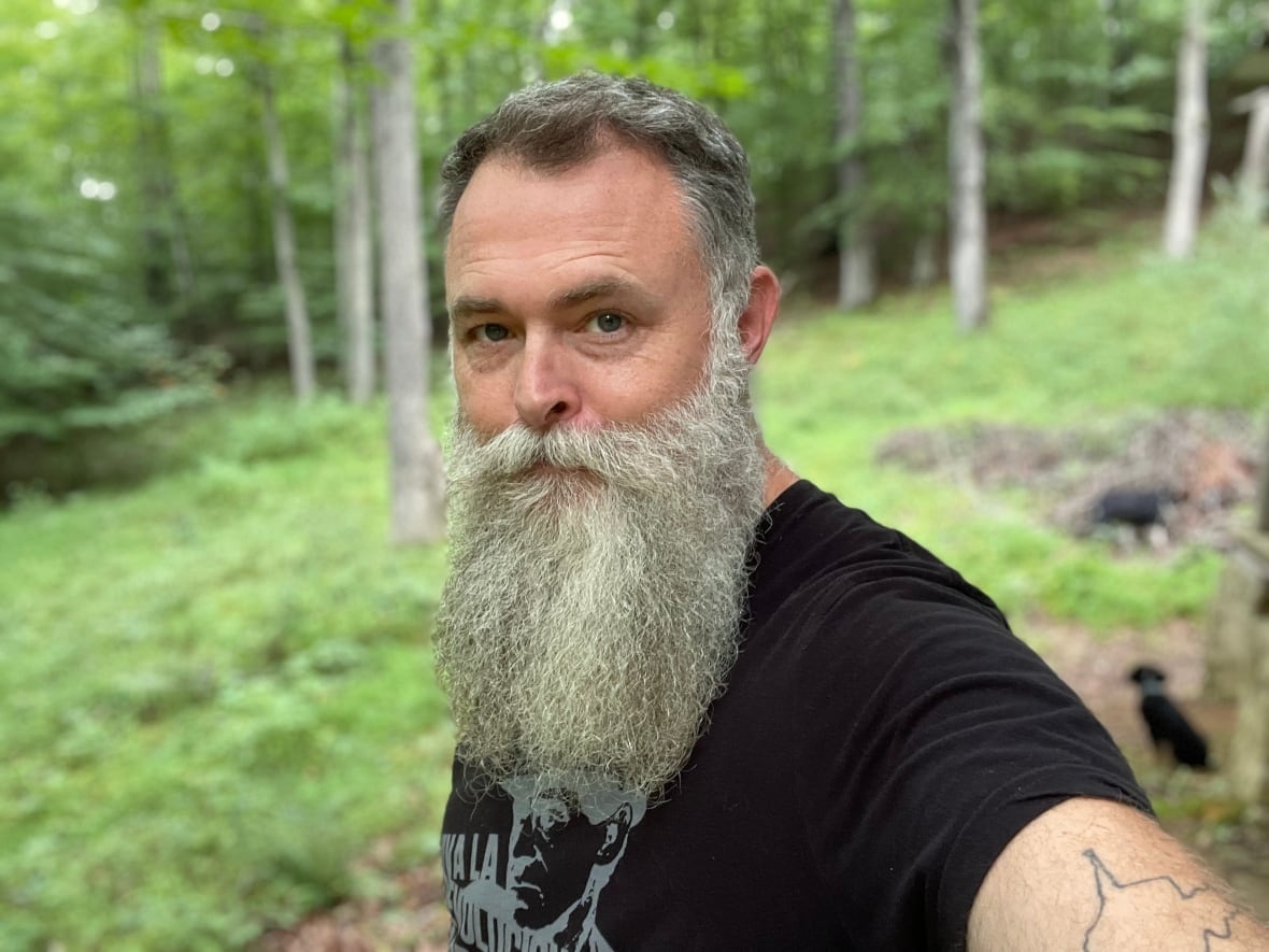 A bearded man takes a selfie outdoors.