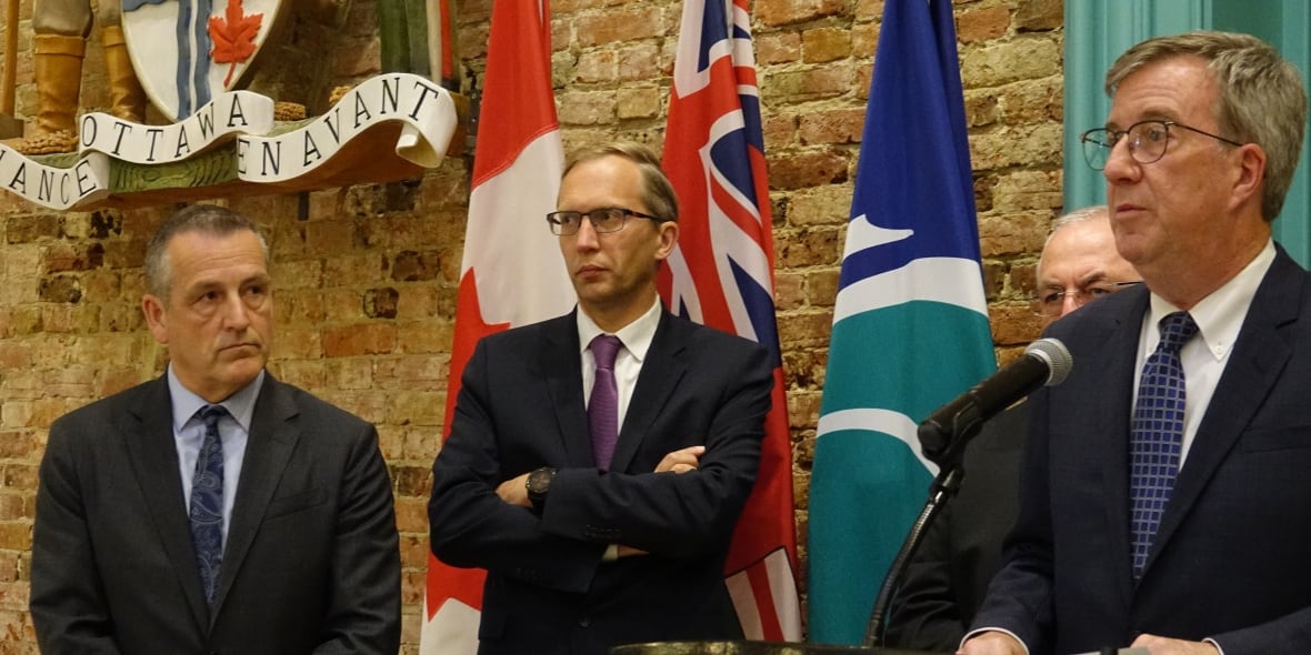 Two company executives and a mayor speak at an event.