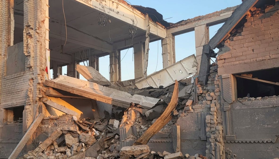 A ruined building is shown with the blue sky vision through a row of blown out windows. 