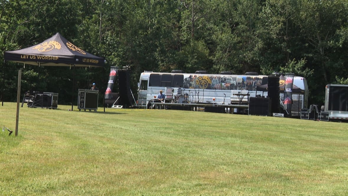 Silver tour bus parked near a wooded area