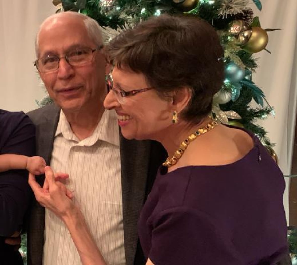 Family poses for picture, woman plays with baby's hand