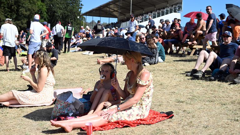 Members of the public keep use an umbrella for shade in the sun at the Goodwood Festival of Speed, West Sussex. Pic: PA 