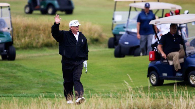 Donald Trump waves to protesters while playing golf at Turnberry golf club, in  2018