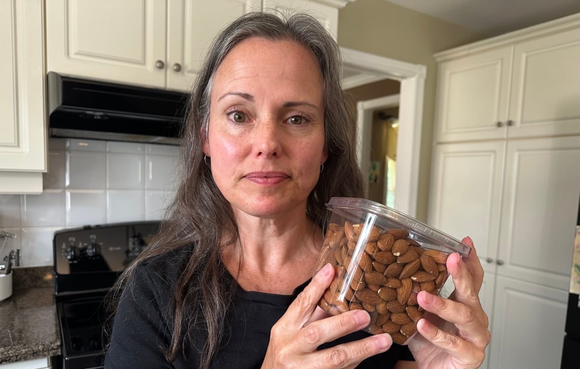 Stacey Dineen holding a container of almonds. 