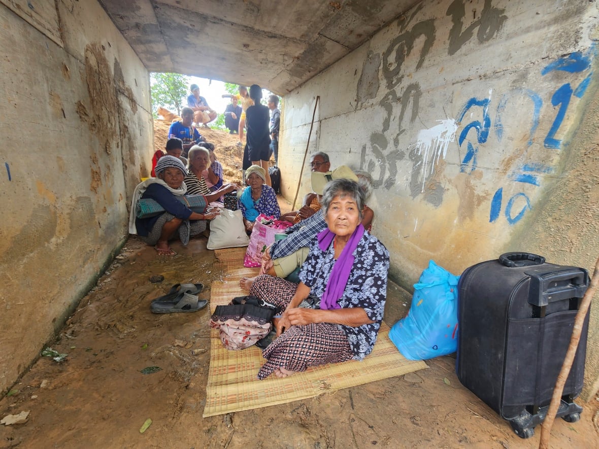 Several people, many elderly, sit on blankets inside a tunnel.