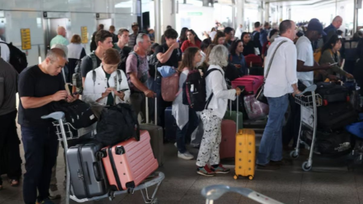 Passengers stand with their luggage, after radar failure led to the suspension of outbound flights across the UK,