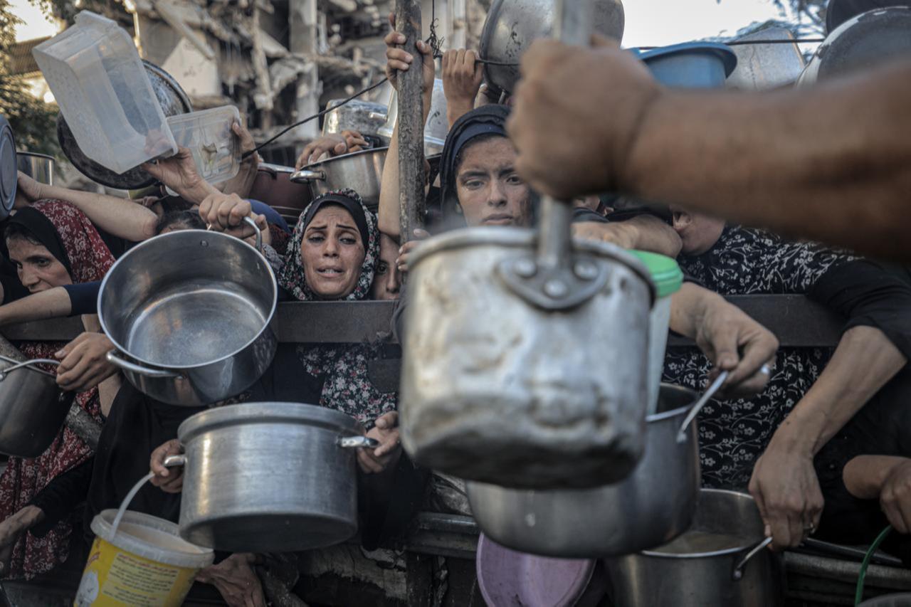 Palestinians, including children wait in line to receive hot meals distributed by the charity organization in Gaza City, Gaza, July 20, 2025. (AA Photo)