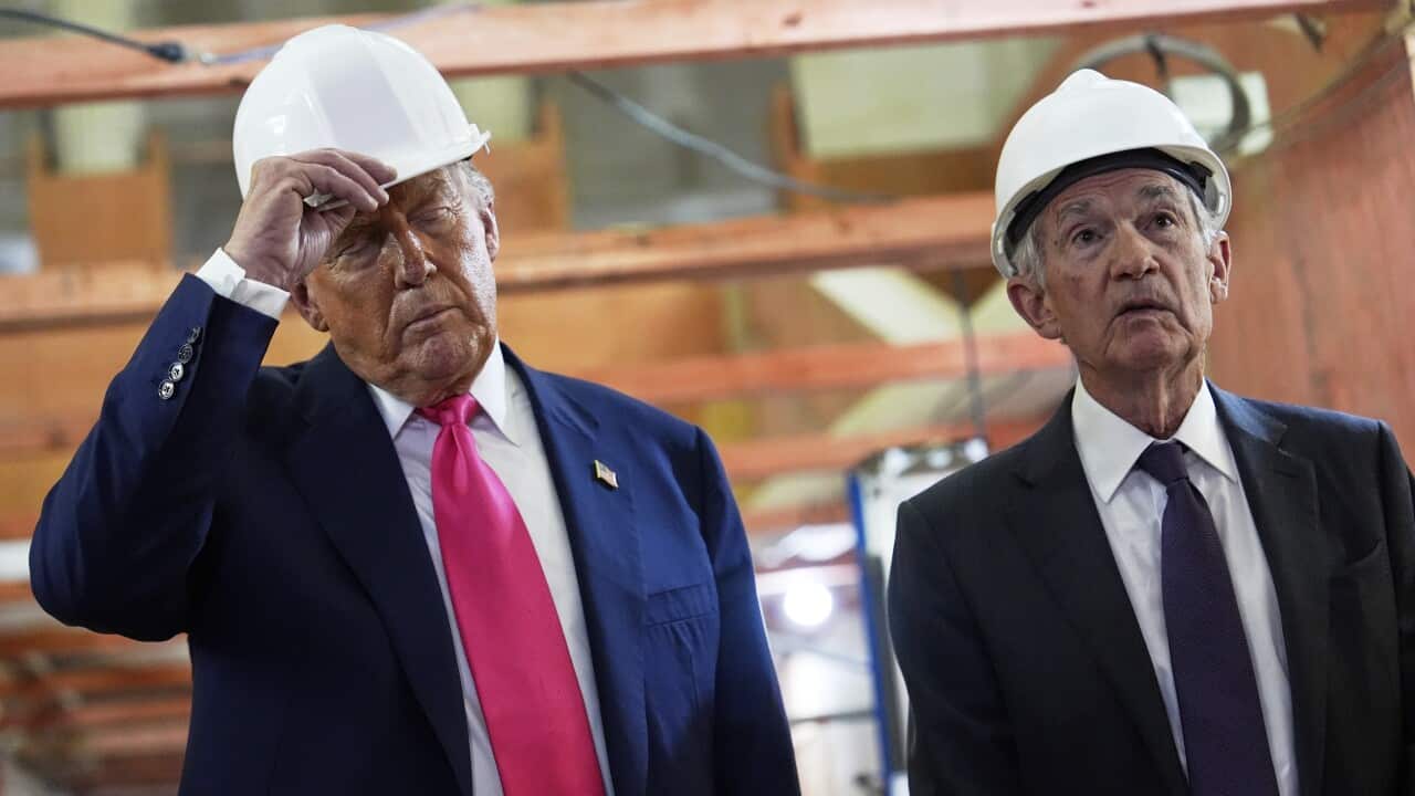 Two men, wearing suits, ties, and hard hats, are speaking.