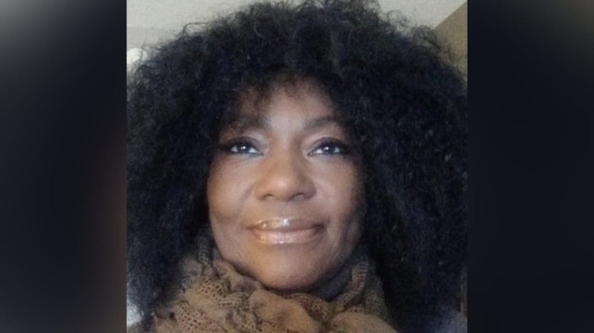 A woman wearing a scarf smiles.