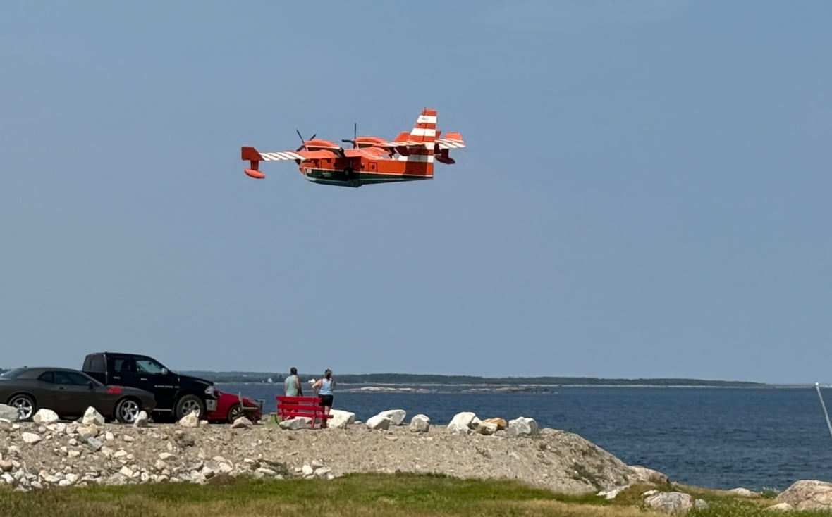 Orange plane in sky with people watching below