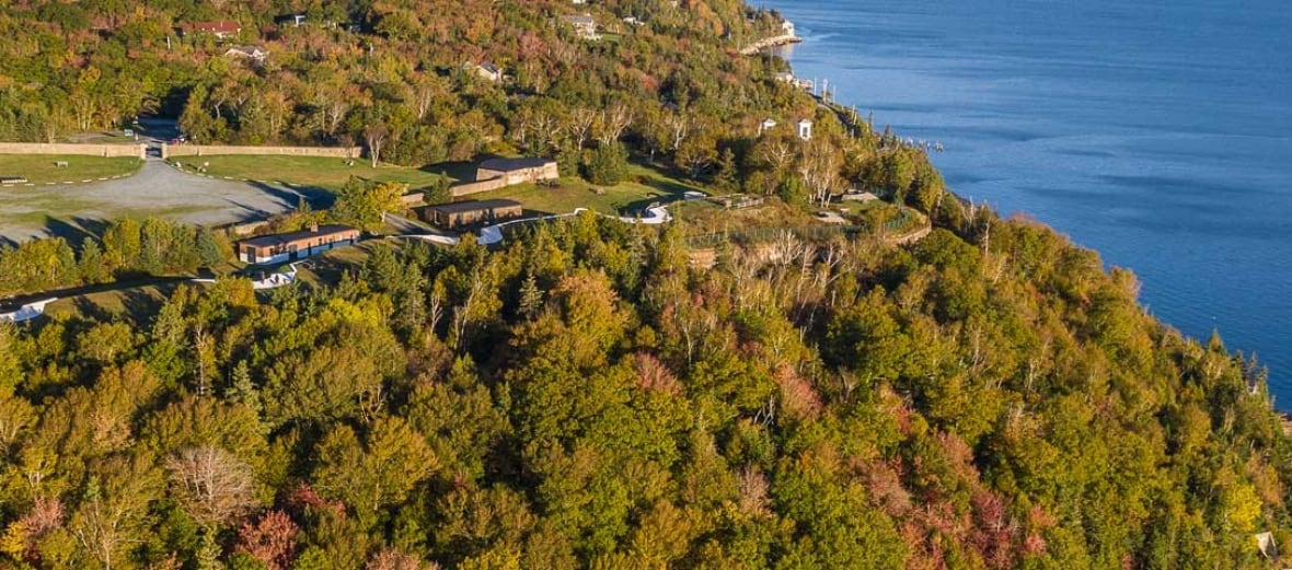 A drone shot of a fortification on a hill overlooking the ocean.