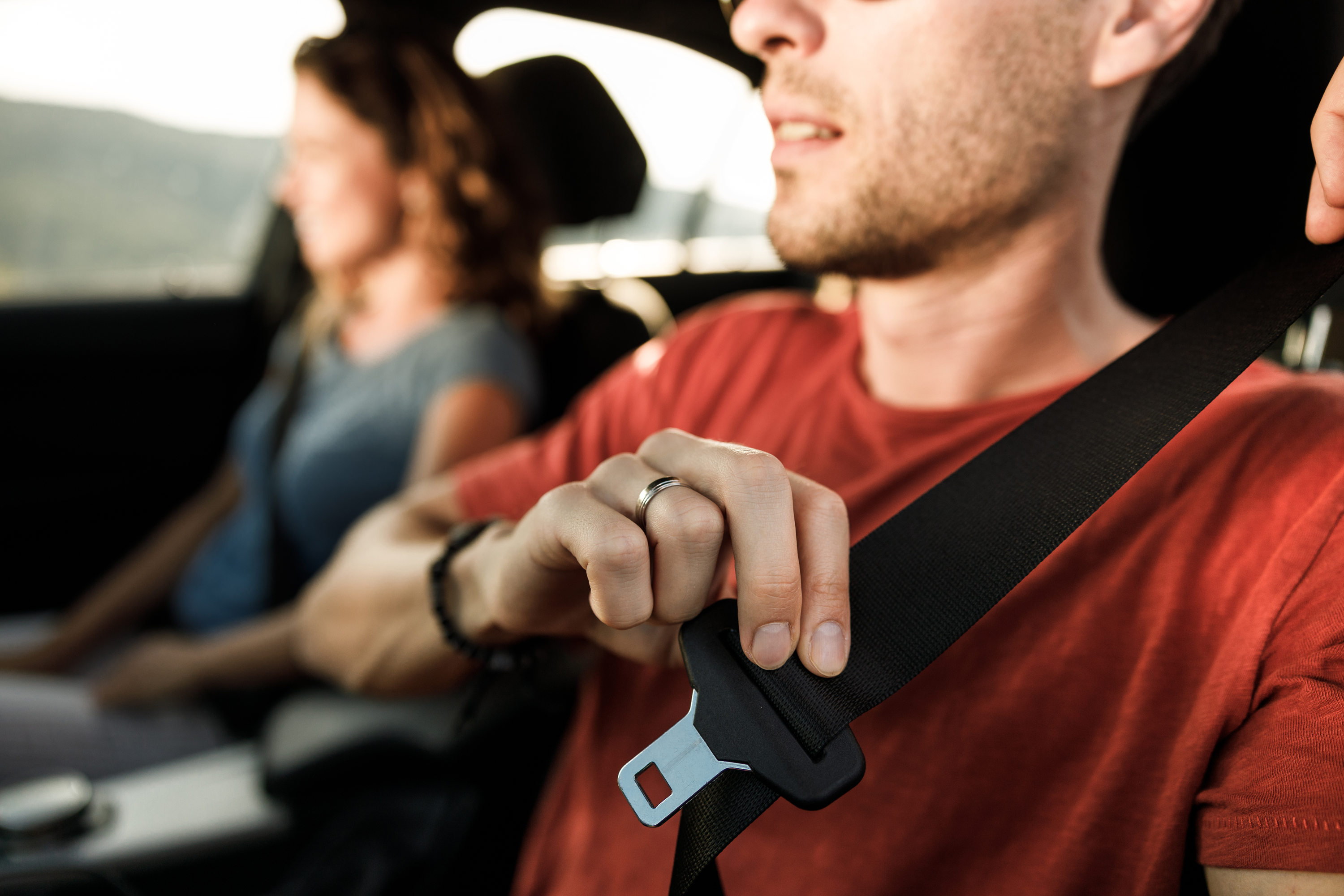 Close-up of a person fastening a seatbelt in a car.