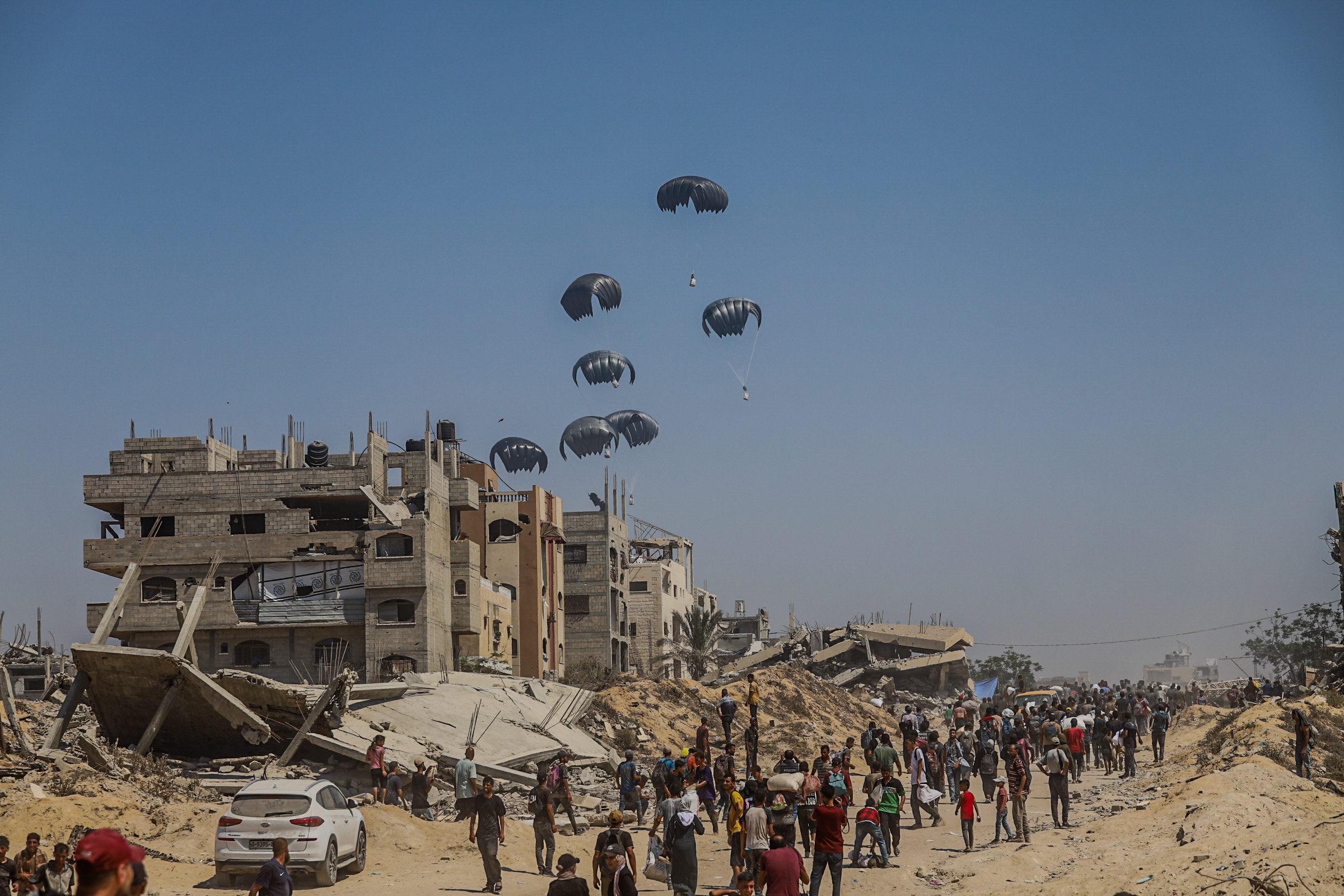 Palestinians receiving humanitarian aid via airdrop in Gaza.