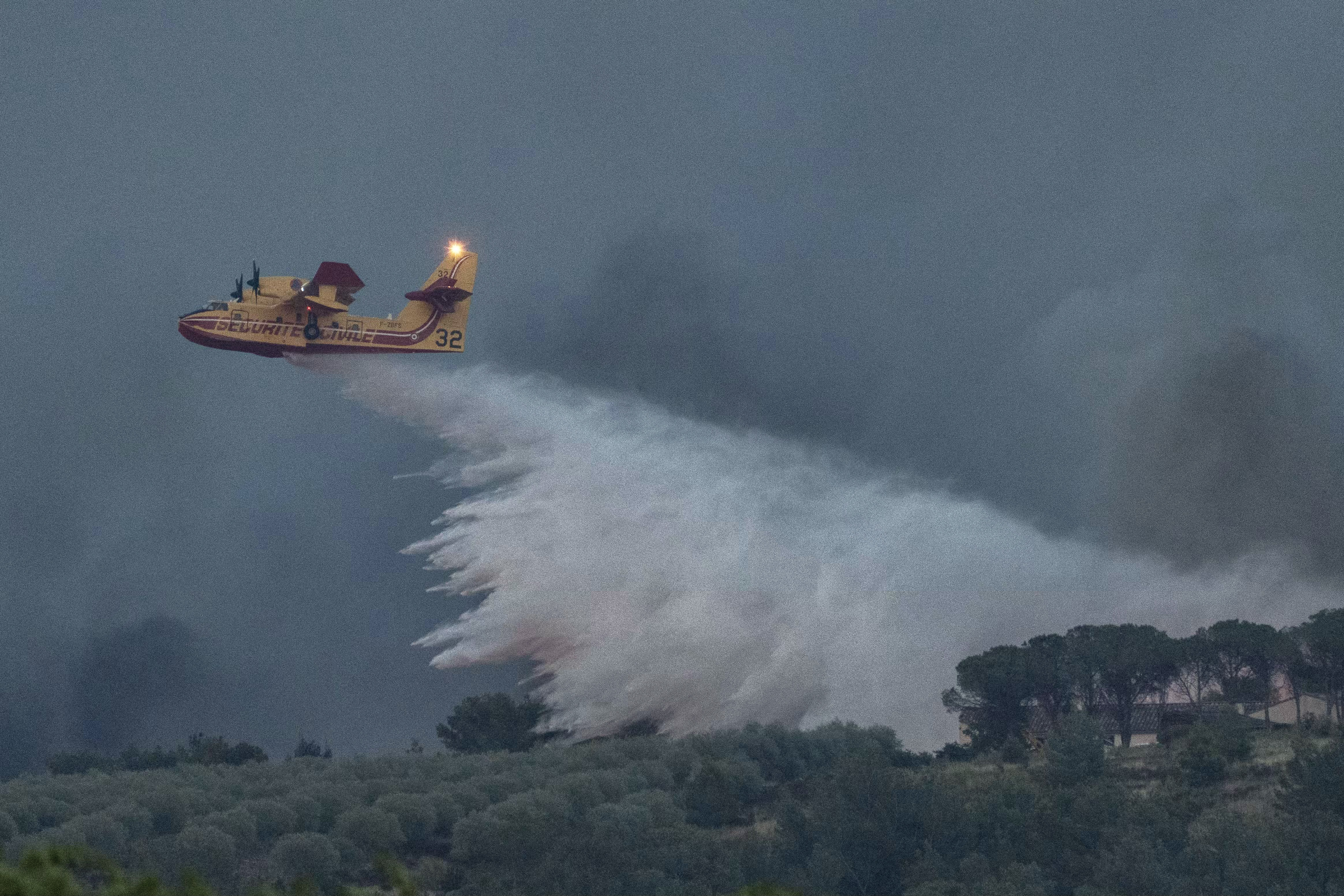 Firefighting plane dropping water on a wildfire.