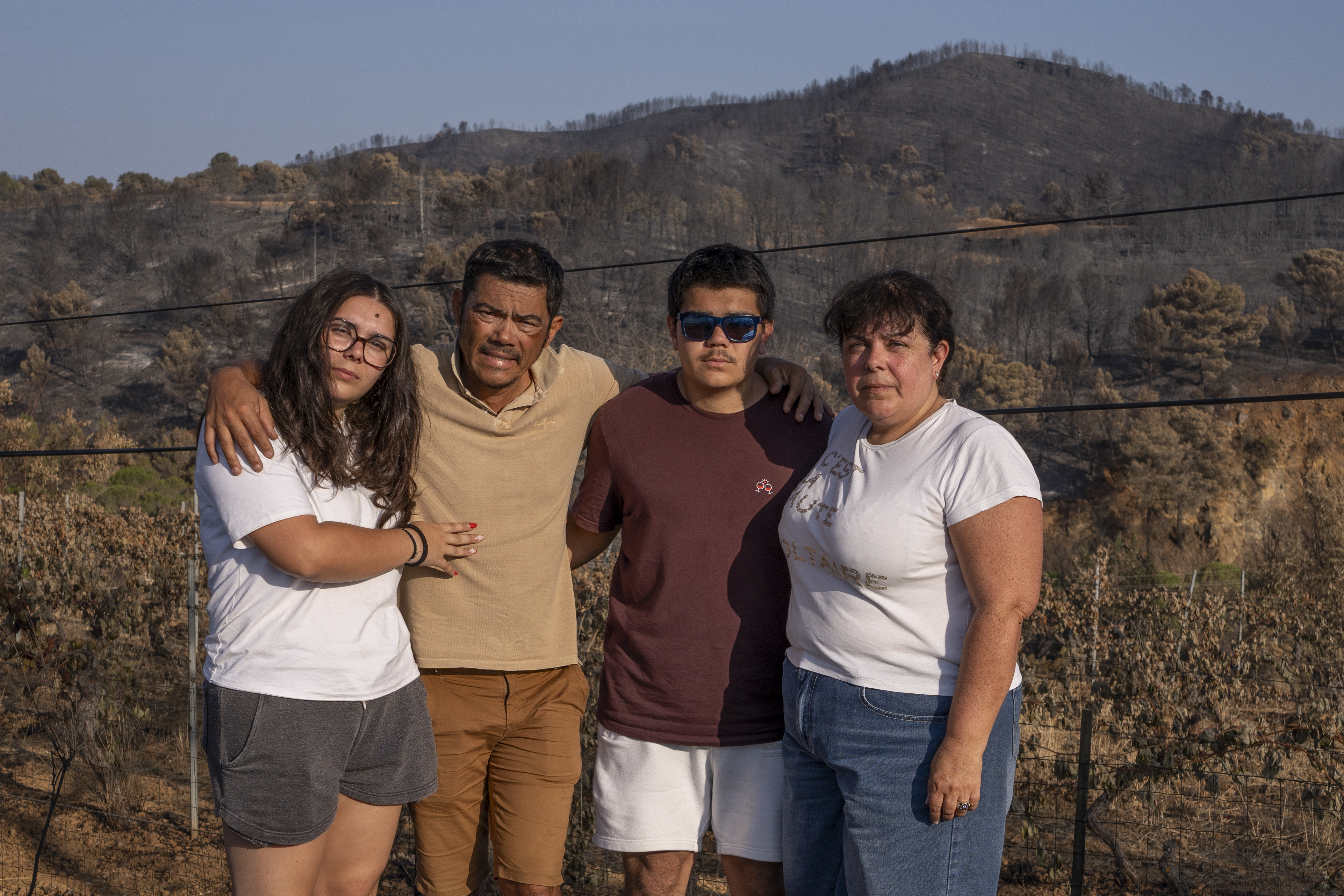 The Dubois family stands in front of their fire-damaged vineyard.
