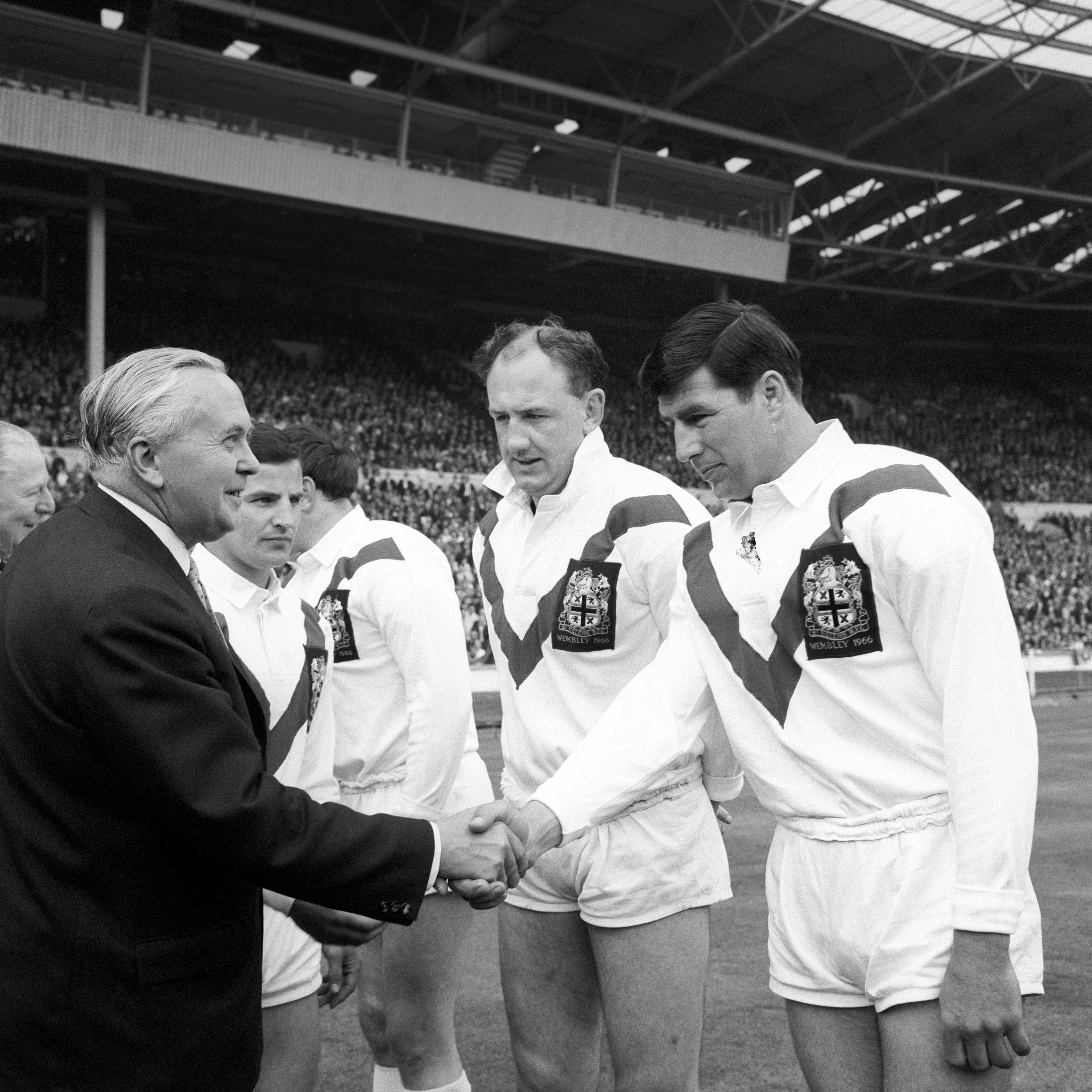 Prime Minister Harold Wilson shaking hands with St. Helens rugby players before a match.