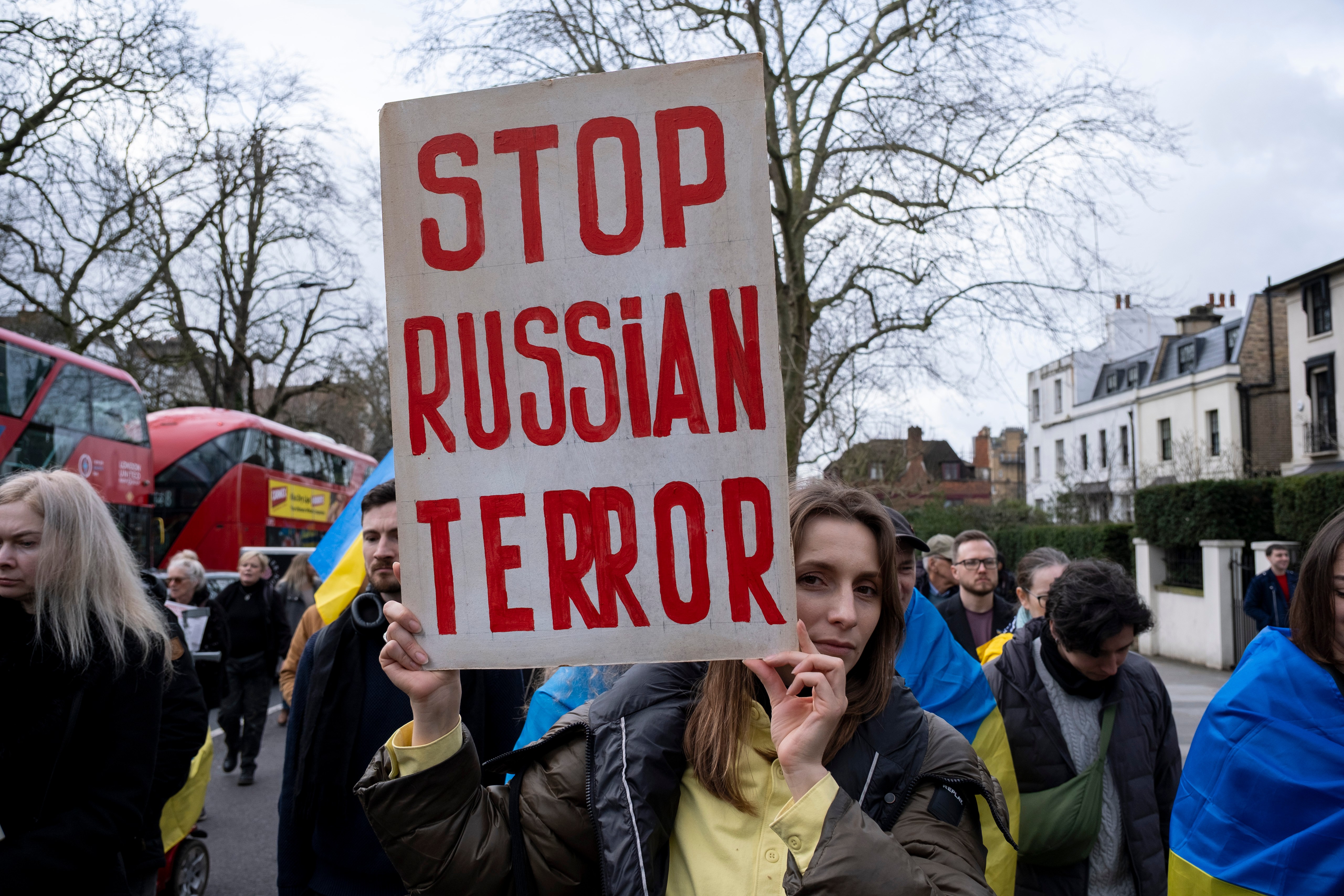 Protestor in London holds a sign reading "Stop Russian Terror."