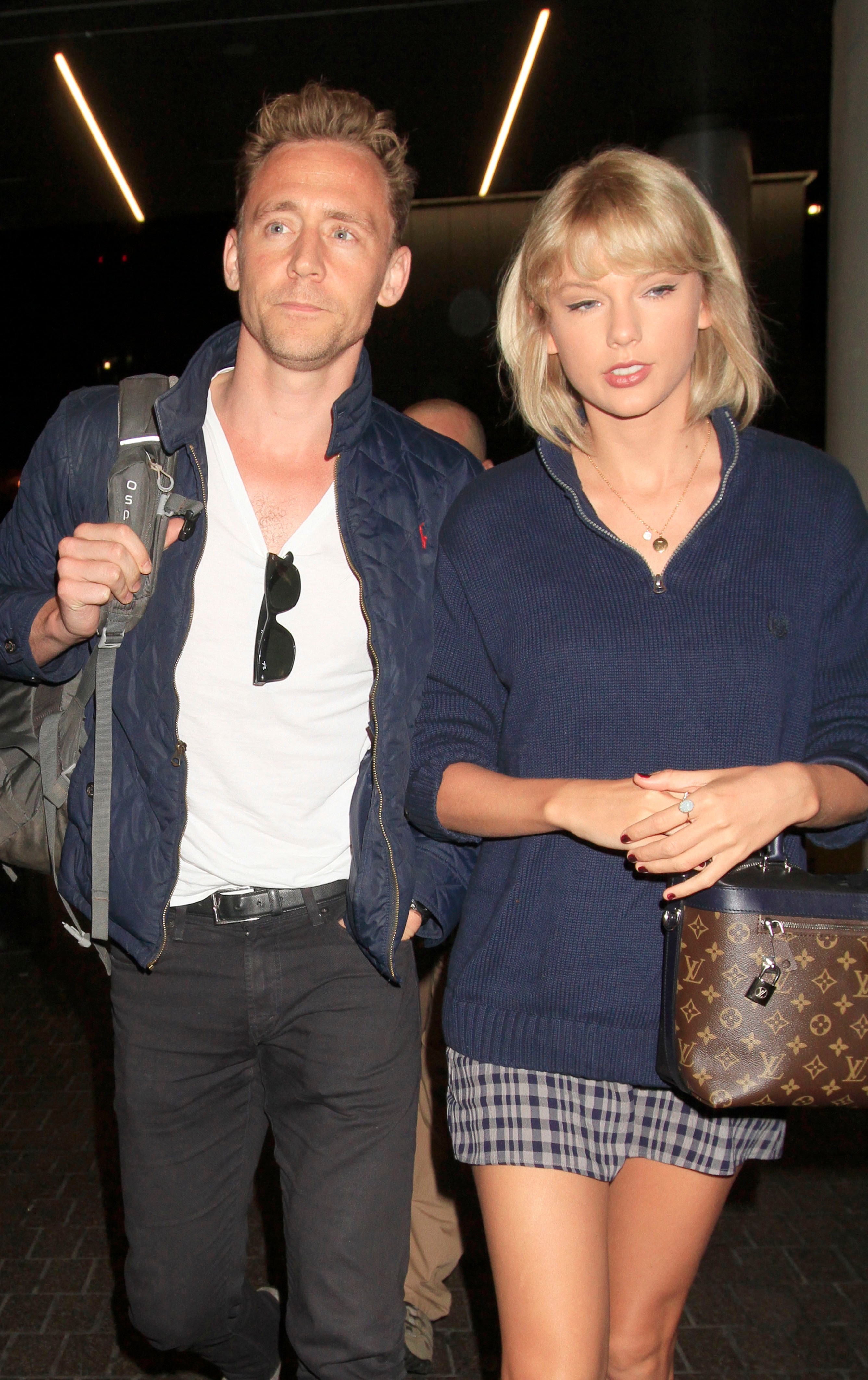 Taylor Swift and Tom Hiddleston walking side-by-side at an airport.