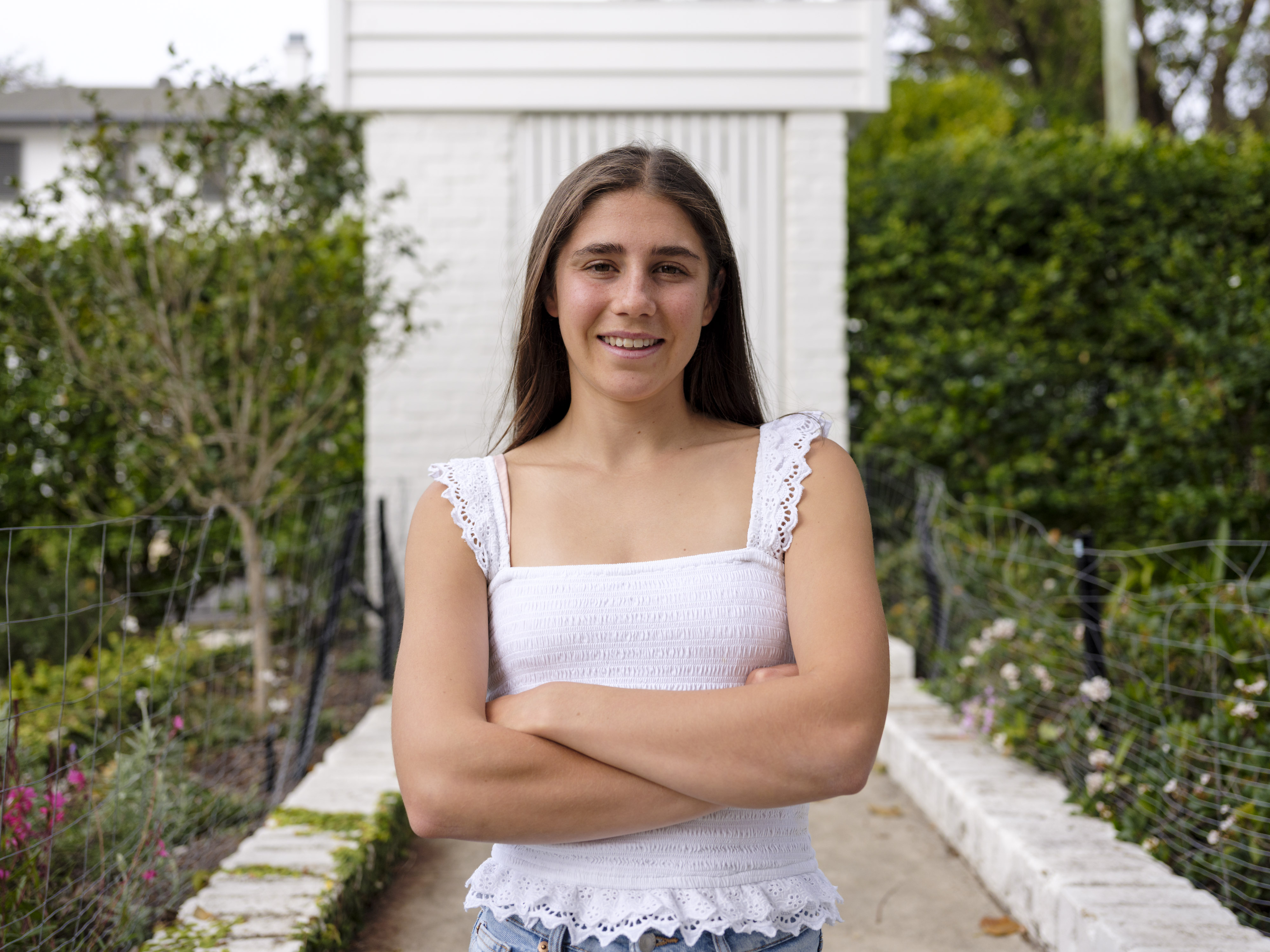 Portrait of a smiling young woman with her arms crossed.