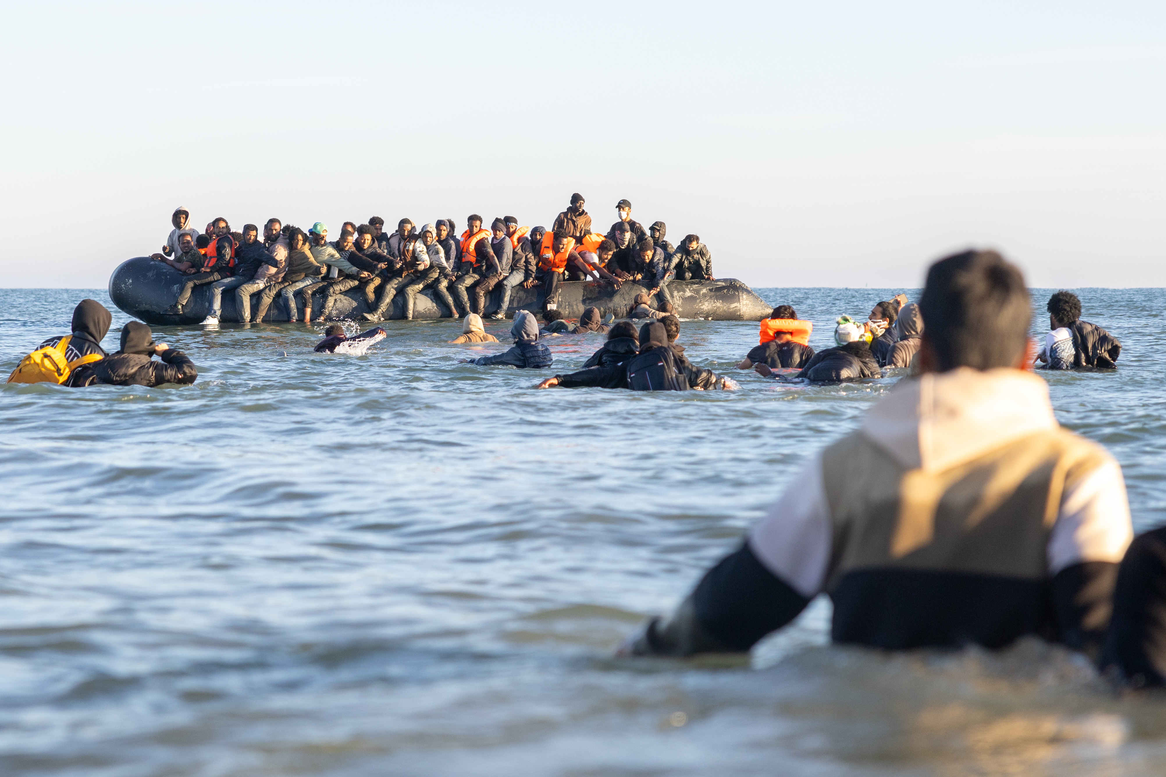 Migrants boarding a small boat in the water.