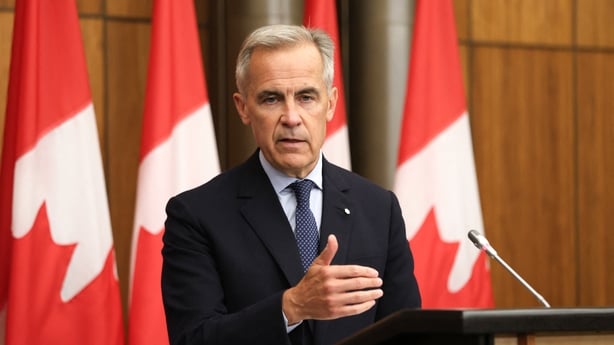 a person standing at a podium with a microphone and a flag behind him