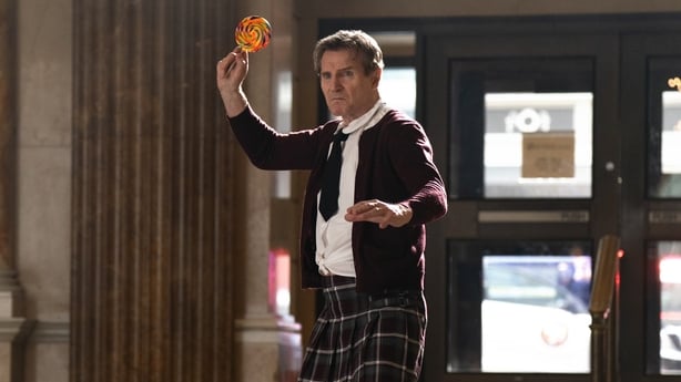 Liam Neeson holds a lollipop in The Naked Gun