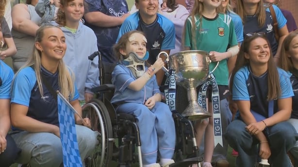 A child in a wheelchair lifts the Brendan Martin cup with a group of others in hospital