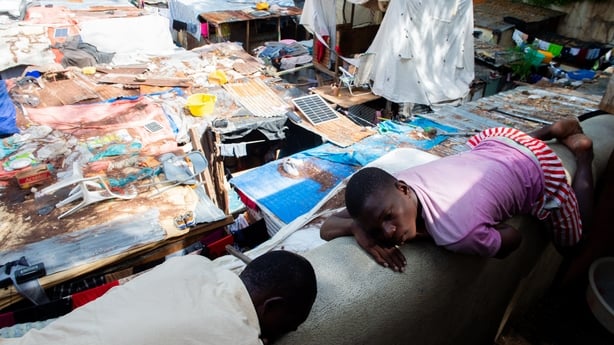 People sleep on a wall in a displaced persons camp set up at a Mormon Church in Port-au-Prince, Haiti, on June 23, 2025