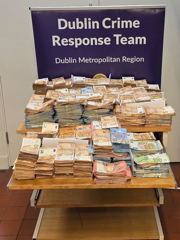 A bundle of cash seized by gardai is displayed on a table 