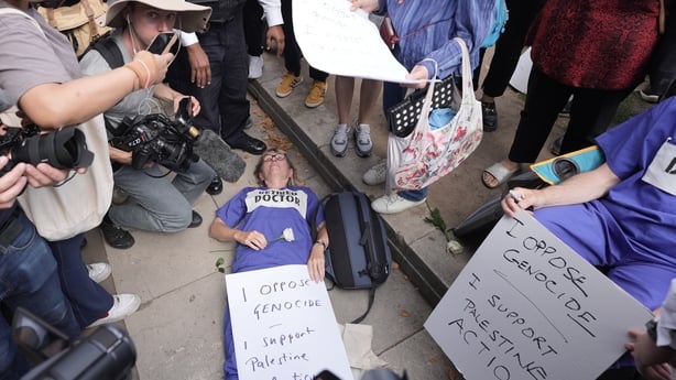 a woman likes on the ground with a placard which reads I oppose genocide I support Palestine Action on top of her