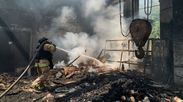 Rescuers from the Emergency Services of Ukraine extinguish a blaze in the aftermath of a Russian drone strike on a warehouse 