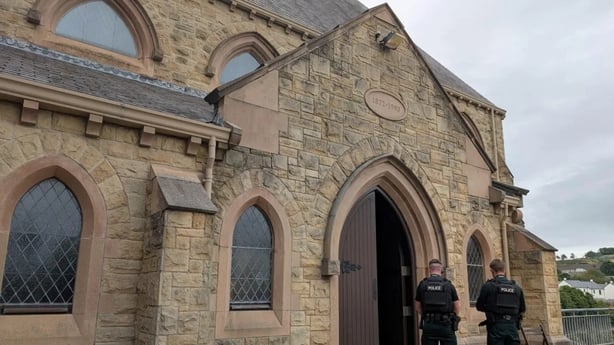 Two PSNI officers in front ofSt Patrick's Church in Downpatrick against a grey, cloudy sky