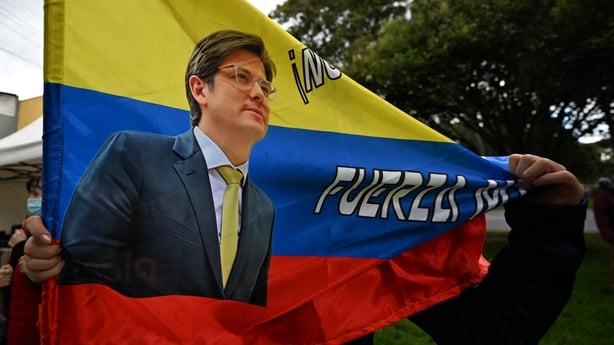A woman holds a Colombian flag with the image of Colombian presidential candidate Miguel Uribe