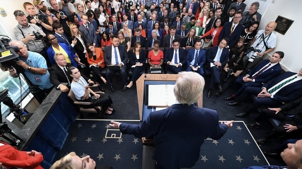 A man in a suit speaks to a room full of people